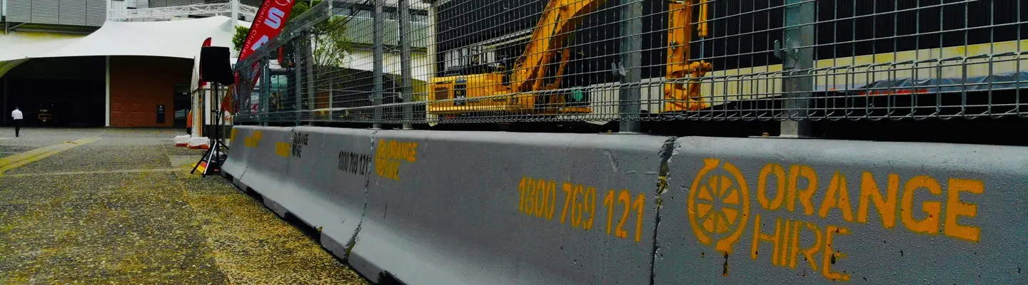 Concrete safety barriers lined up on a construction site, supplied by Orange Hire for traffic and site protection.