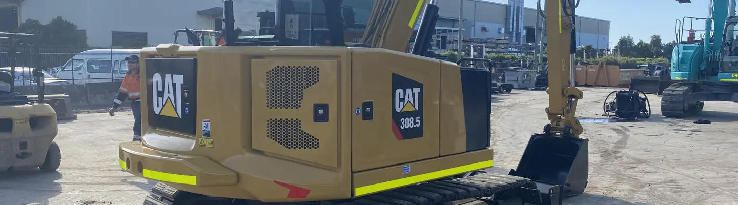 Man standing beside excavators at a construction site, overseeing work related to safety barrier or rail installation.