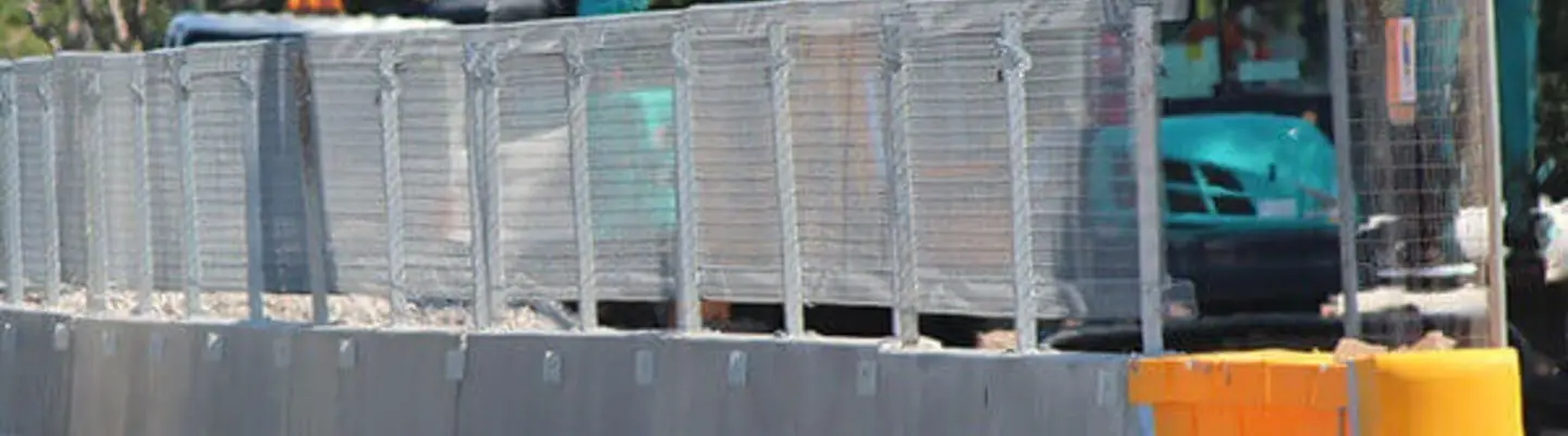 Safety barriers installed along a roadside construction area to protect workers and guide traffic through the work zone.