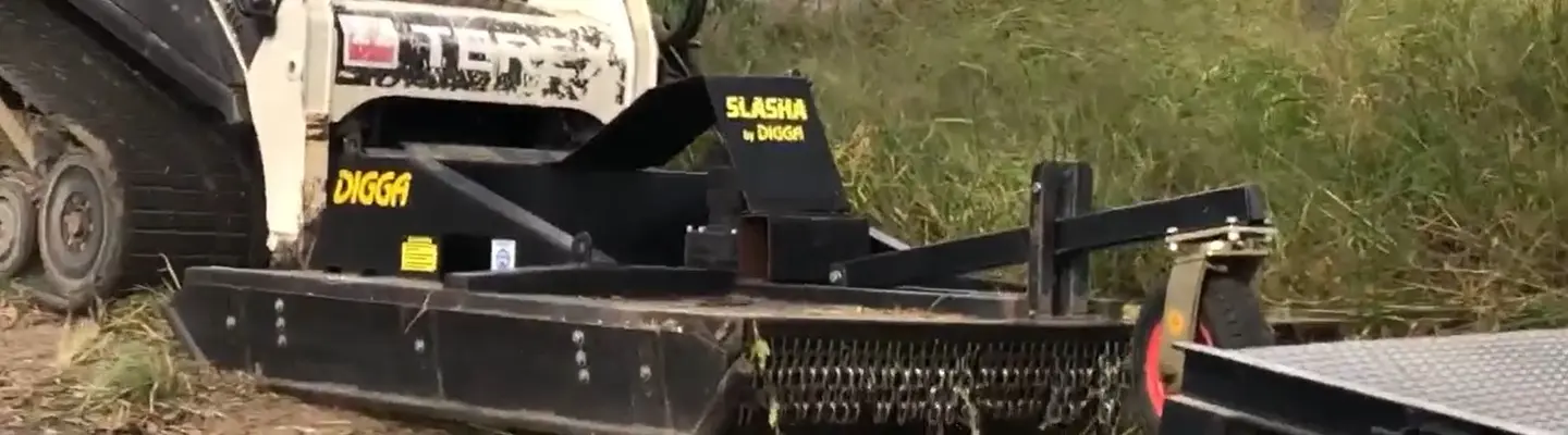 A machine trimming grass in an open field, highlighting land maintenance and safety near construction zones.