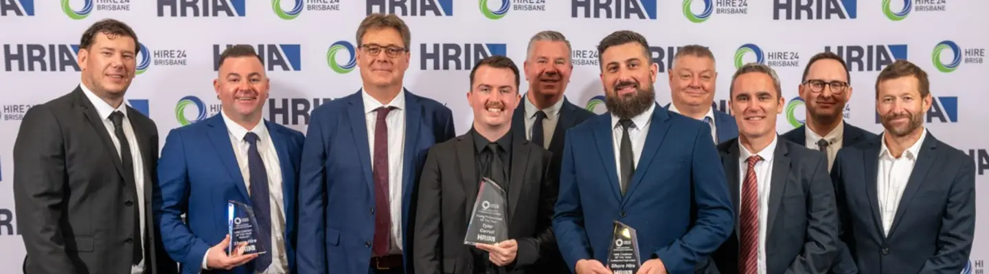Group of employees smiling and holding an award plaque, celebrating recognition and company achievements.