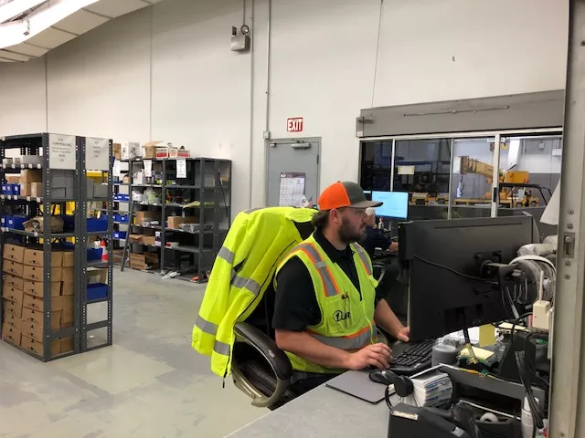 employee wearing high visibility vest sitting at computer