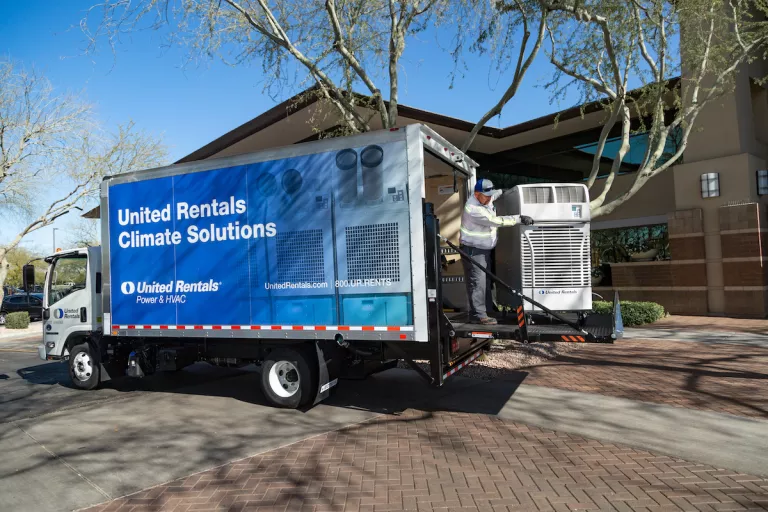 man unloading a spot cooler from the back of a united rentals box truck