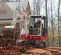 Mini-excavatrice Takeuchi rouge et blanche utilisée pour creuser la terre près d’une maison