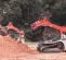 Red and white Takeuchi small track loader digging in a pile of dirt