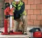 Red and black Hilti concrete core drill vacuum pump assembly being used by a worker