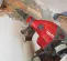Red and black Hilti electric demolition hammer being used to demo a wall