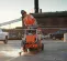 Orange and gray Husqvarna 24 inch Self-propelled Concrete Street Saw in use in a parking lot