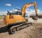 Orange Case excavator digging and lifting dirt next to the parking area of a business