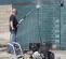 Silver and black Mi-T-M 4,000 psi pressure washer in use by a worker to clean the exterior concrete wall of a building