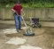 Silver and black Mi-T-M 4,000 psi pressure washer in use by a worker to clean concrete