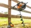 Orange and black Stihl one-man auger leaning against a wood fence with protective gear nearby.