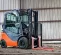 Orange and black warehouse forklift with pneumatic tires in a warehouse