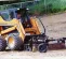yellow skid steer using a rake attachment on dirt