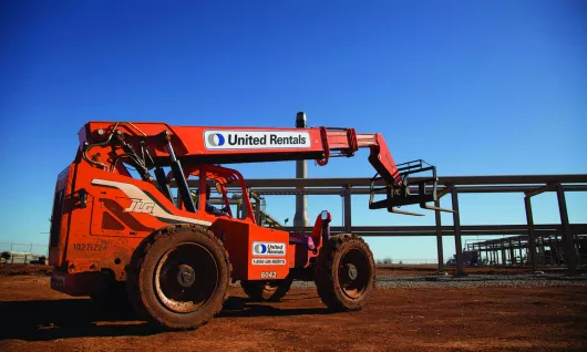 Orange JLG forklift with United Rentals branding against a blue sky
