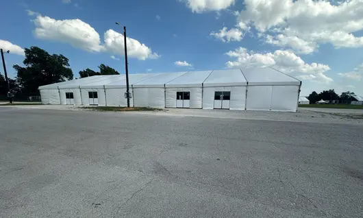 Construction of a fabric structure with a metal frame and a crane in a field, showcasing eco-friendly building practices.