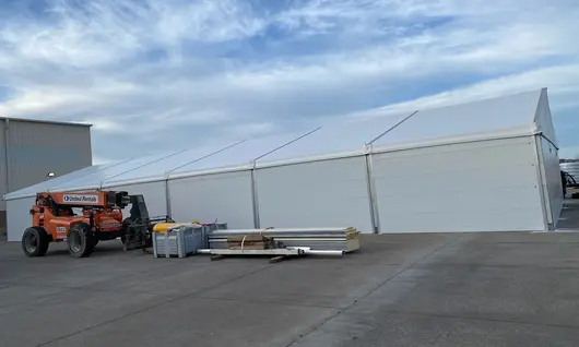 Interior of an industrial tent rental filled with pallets and crates, showcasing ample lighting and custom storage solutions.