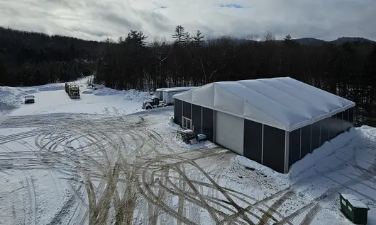 Large construction tent in a snowy outdoor environment, showcasing its durable vinyl cover and climate-controlled design.