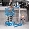 Elevador de tijera eléctrico Blue Genie de 30 – 33 ft con un trabajador en la plataforma junto a un elevador de materiales en un almacén