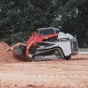 Red and white Takeuchi large track loader lifting dirt from a pile