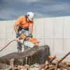 Orange and white Stihl 16 inch cut-off saw cutting through a large piece of stone