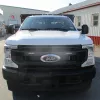 White Ford stake bed truck with 4-wheel drive, a 12-foot bed and a black lift gate parked outside of a business
