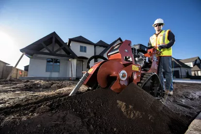 Orange Ditch Witch 48 in. walk-behind trencher in use in front of a home under construction
