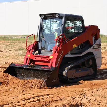 Red and white Takeuchi small track loader spreading dirt