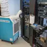 Light blue and white united rentals spot cooler in front of a server in a data center
