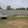 grey shipping container behind golf cart and concrete barriers