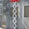 Red MEC wide scissor lift at a work site