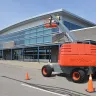 Orange and Gray Skyjack 45 ft.-47 ft.Telescopic with boom upright parked in front of building