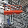 Elevador de tijera eléctrico Skyjack naranja y gris en un sitio de trabajo