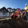 Orange Ditch Witch 48 in. walk-behind trencher in use in front of a home under construction