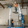 Blue Genie 16-18 ft. manual material lift being used next to a vertical mast lift in a warehouse