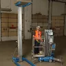 Blue Genie 16-18 ft. manual material lift holding a light fixture in a warehouse