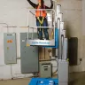 Blue Genie 15 ft. electric powered partially extended vertical mast lift with a worker on the platform