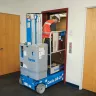 Blue Genie 20 ft. electric powered unextended vertical mast lift moving through an interior doorway