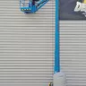 Blue Genie 26 ft. vertical mast boom lift fully extended and in use next to a building