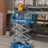 Blue Genie 20 ft. electric scissor lift extended next to a building