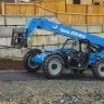 Blue Genie 8,000 lb. telehandler reach forklift parked on asphalt next to a cement barrier