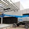 Blue Genie 4WD telescopic boom lift with boom raised and workers on the platform at construction site