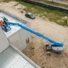 Blue Genie 4WD telescopic boom lift with boom upright and workers on the platform at construction site