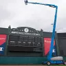 Blue Genie 135 ft. 4WD extended telescopic boom lift inside a sports arena