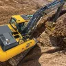 Yellow and black John Deere excavator digging a trench with dirt in its bucket
