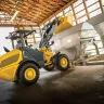 Yellow and black John Deere wheel loader dumping material into a container