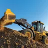 Yellow and black John Deere 4WD wheel loader dumping a load of dirt into a pile
