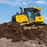 Yellow and black John Deere bulldozer with low ground pressure on a pile of dirt with a worker in the cab
