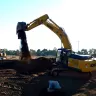 Yellow and black Kobelco excavator digging dirt at job site