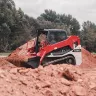 Red and white Takeuchi small track loader carrying dirt